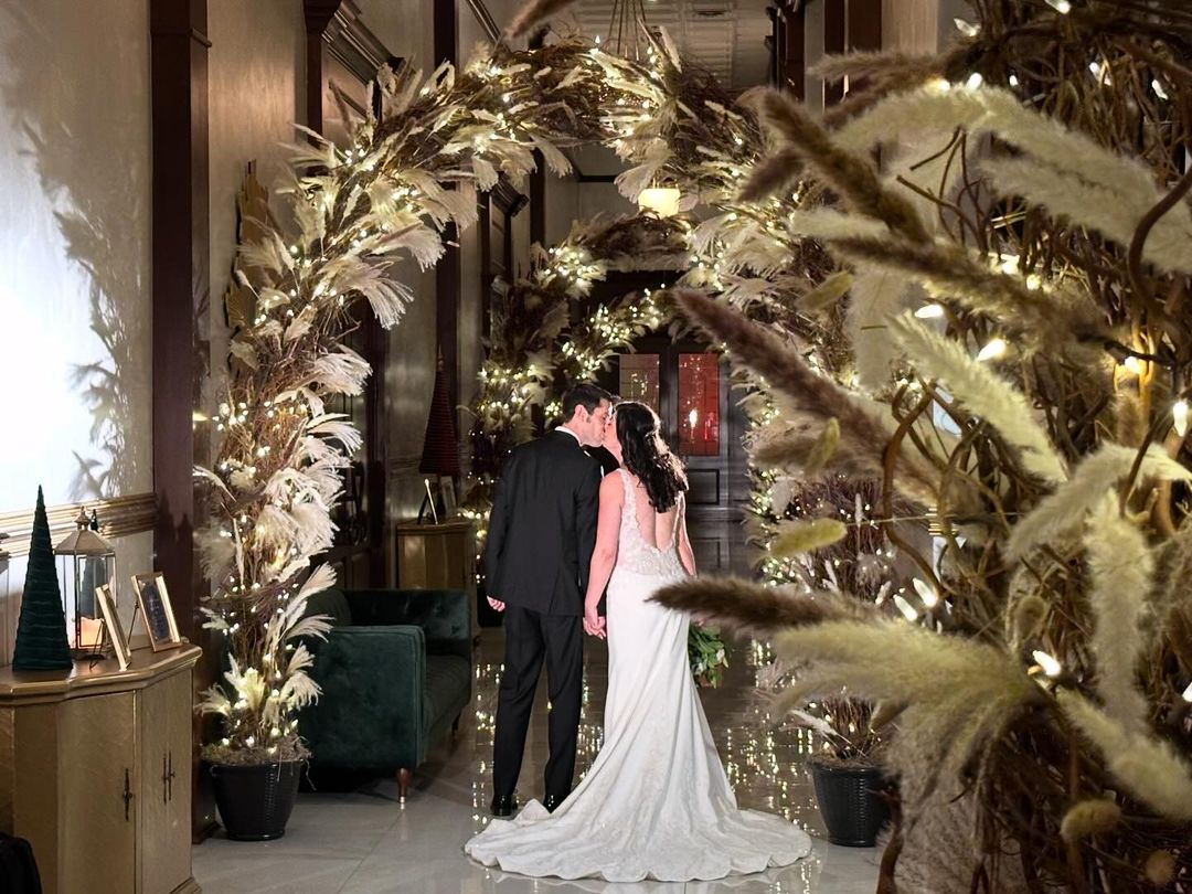 Newlyweds kissing under archway